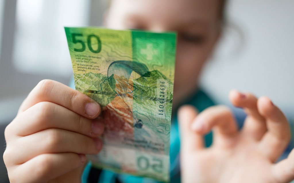 Una bambina guarda una banconota da 50 franchi